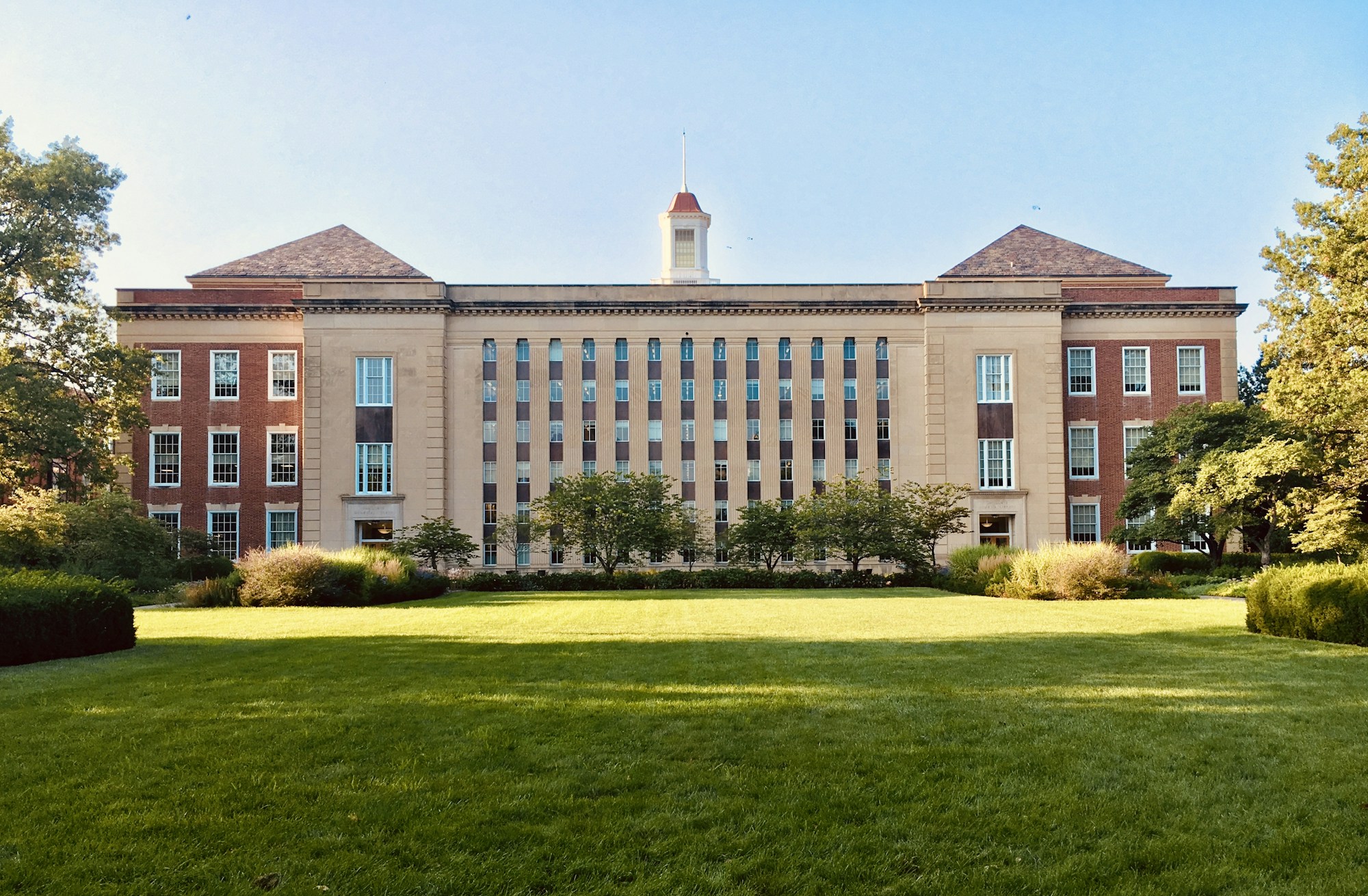 A university building with classic brick architecture and a manicured lawn represents higher education.